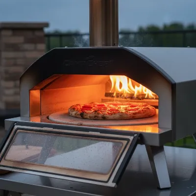 Camp Chef Artisan Pizza Oven baking a delicious, crispy pizza outdoors with a bright flame visible