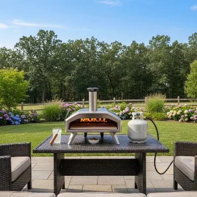 Camp Chef Artisan Pizza Oven on a patio table with accessories in a sunny backyard setting