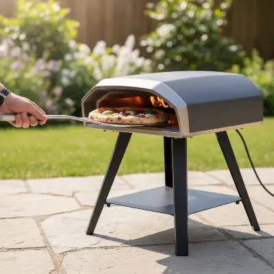 A sleek, modern portable gas pizza oven on a stand outdoors, with a pizza being inserted